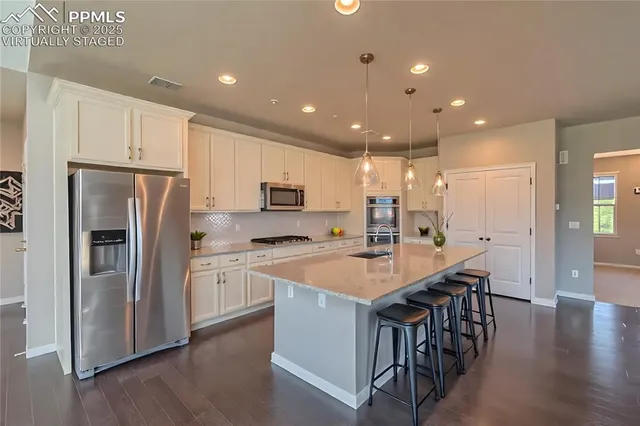 a kitchen with stainless steel appliances granite countertop a table chairs sink refrigerator and microwave