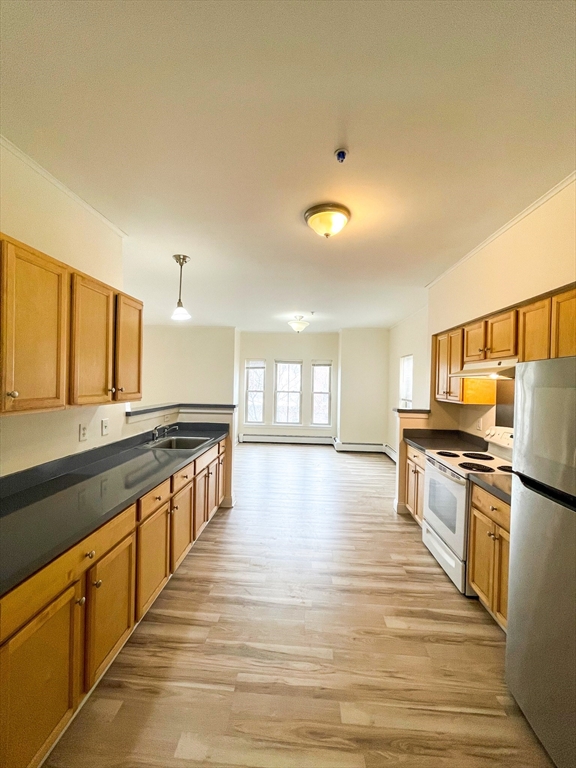 a large kitchen with stainless steel appliances a stove a sink dishwasher and a oven with wooden floor