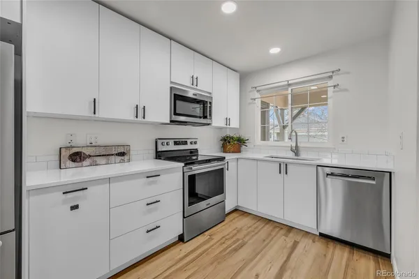 a kitchen with cabinets stainless steel appliances a sink and a window