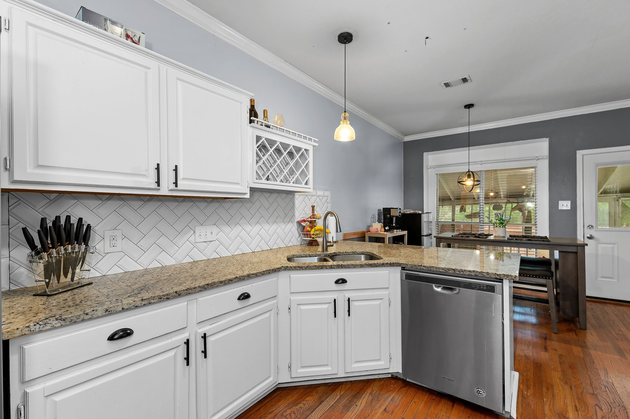 11737 Rydalwater Lane Austin, TX 78754 - Photo 25 of 40 Corner kitchen featuring white cabinetry, granite countertops, a herringbone tile backsplash, and stainless steel appliances