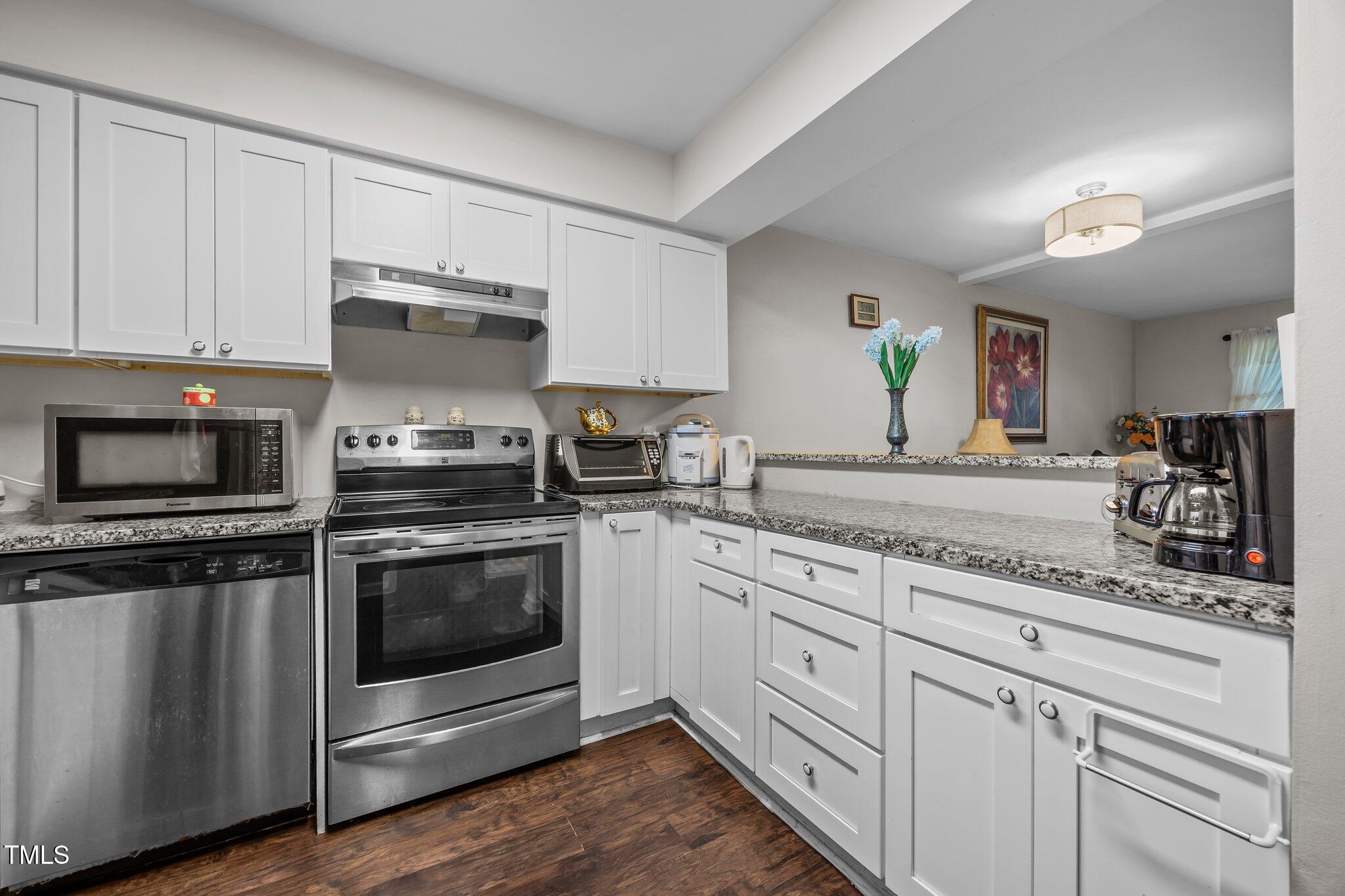 7020 Longstreet Drive, Unit A Raleigh, NC 27615 - Photo 7 of 27 a kitchen with granite countertop white cabinets and stainless steel appliances