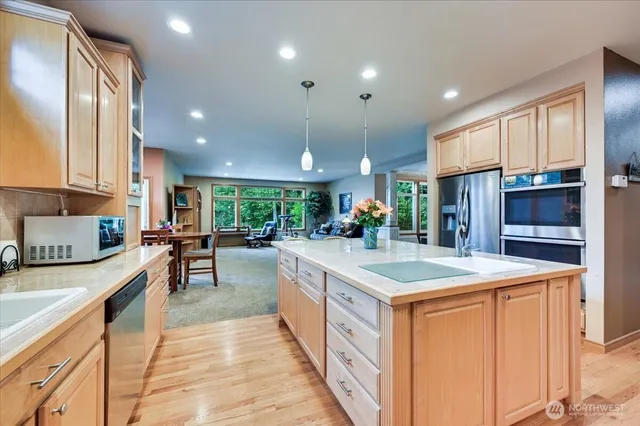 a large kitchen with kitchen island a large counter top stainless steel appliances and cabinets
