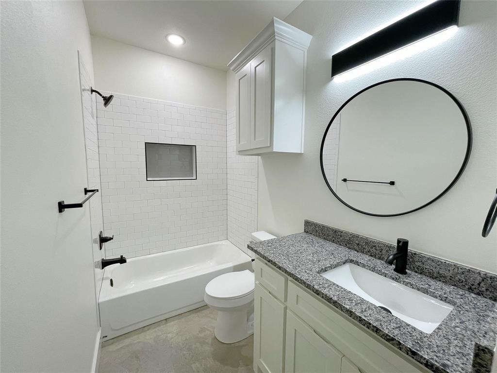 607 West Baker Street Denison, TX 75020 - Photo 14 of 19 Full bathroom featuring vanity, toilet, and tiled shower / bath