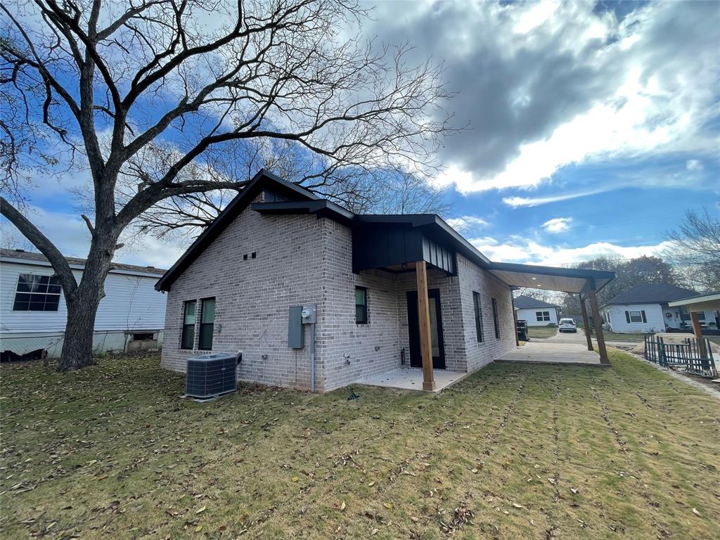 607 West Baker Street Denison, TX 75020 - Photo 18 of 19 View of side of home with central air condition unit, a patio, and a yard