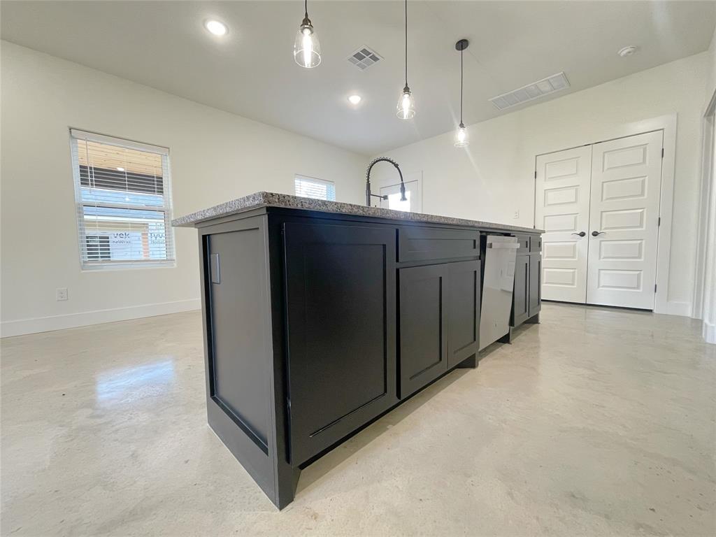 607 West Baker Street Denison, TX 75020 - Photo 5 of 19 Kitchen featuring light stone countertops, sink, a kitchen island with sink, hanging light fixtures, and dishwashing machine