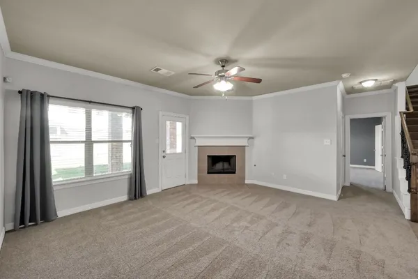 a view of an empty room with chandelier fan and fire place