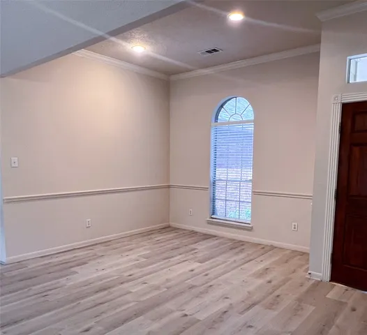 an empty room with wooden floor cabinet and windows