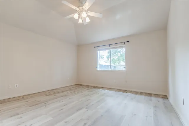 an empty room with wooden floor closet and fan