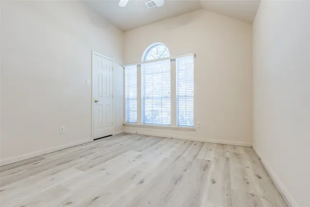 a view of an empty room with a window and wooden floor