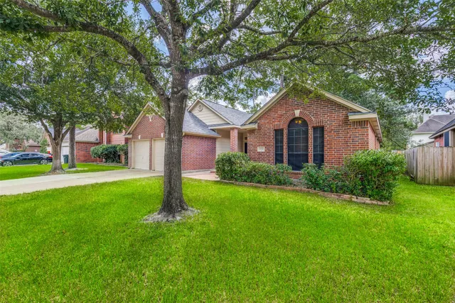 a front view of a house with a yard and large tree