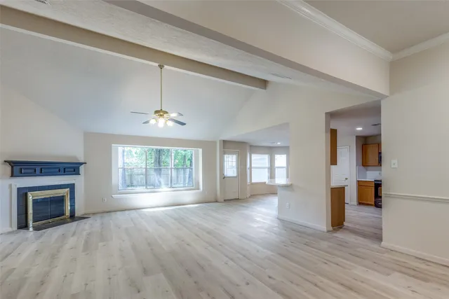 an empty room with wooden floor fireplace and windows