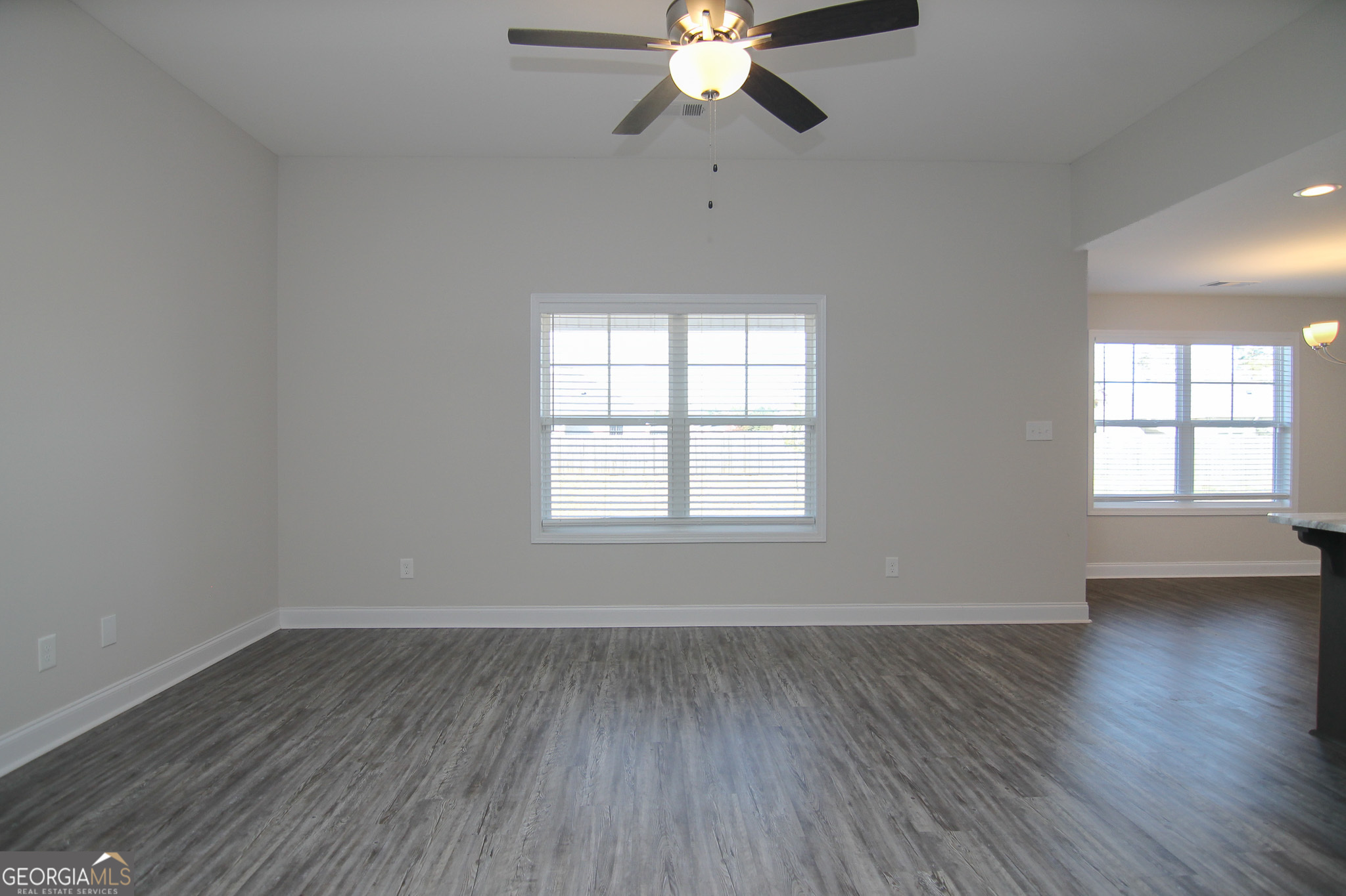 138 Sadie Heights Boulevard Perry, GA 31069 - Photo 4 of 31 an empty room with wooden floor chandelier fan and windows