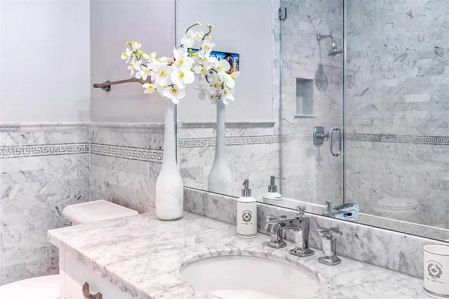 a bathroom with a granite countertop sink a mirror and a shower