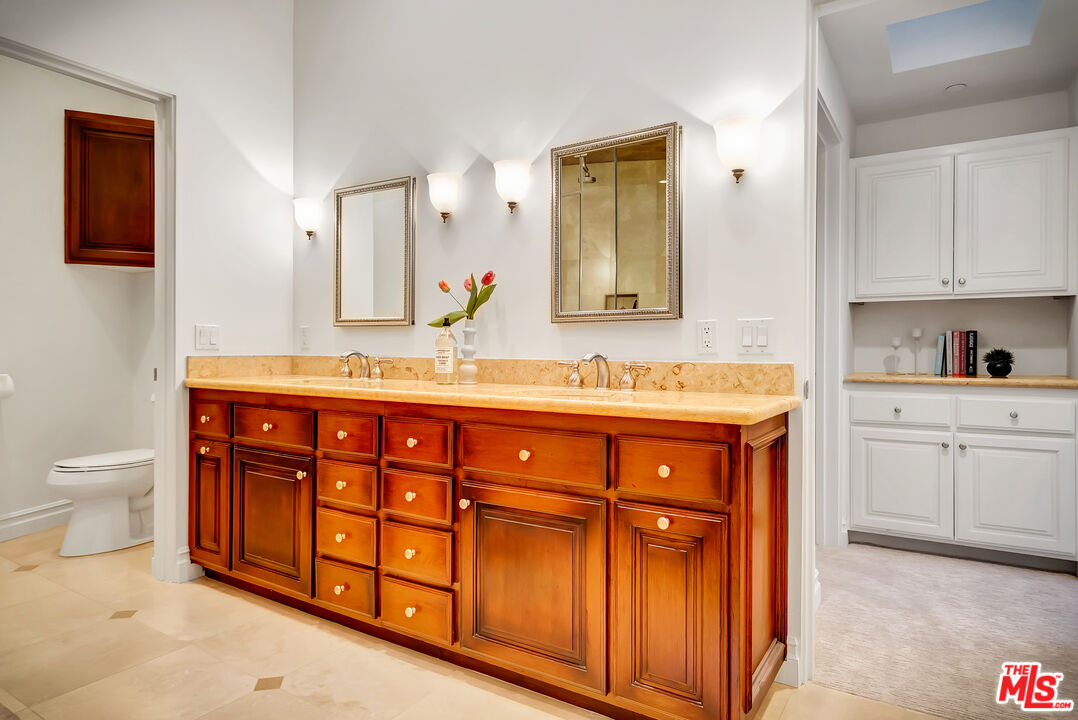 16561 Adlon Road Encino, CA 91436 - Photo 48 of 75 a bathroom with a granite countertop double vanity sink a mirror and a toilet