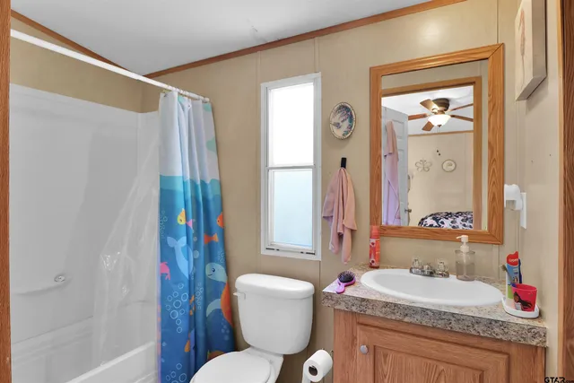 a bathroom with a granite countertop sink toilet a mirror and shower