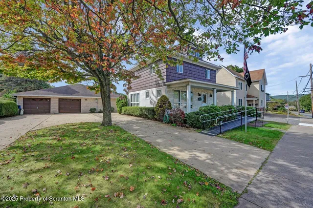 a front view of a house with a garden and trees