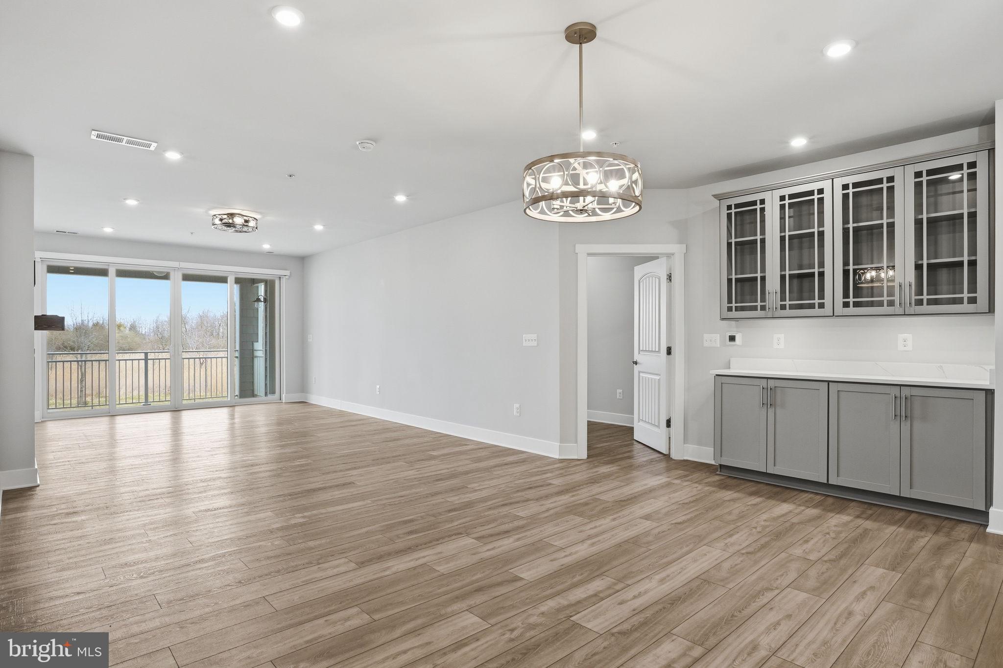111 Marshgrass Way, Unit 22 Chester, MD 21619 - Photo 12 of 102 a view of an empty room with wooden floor and kitchen view