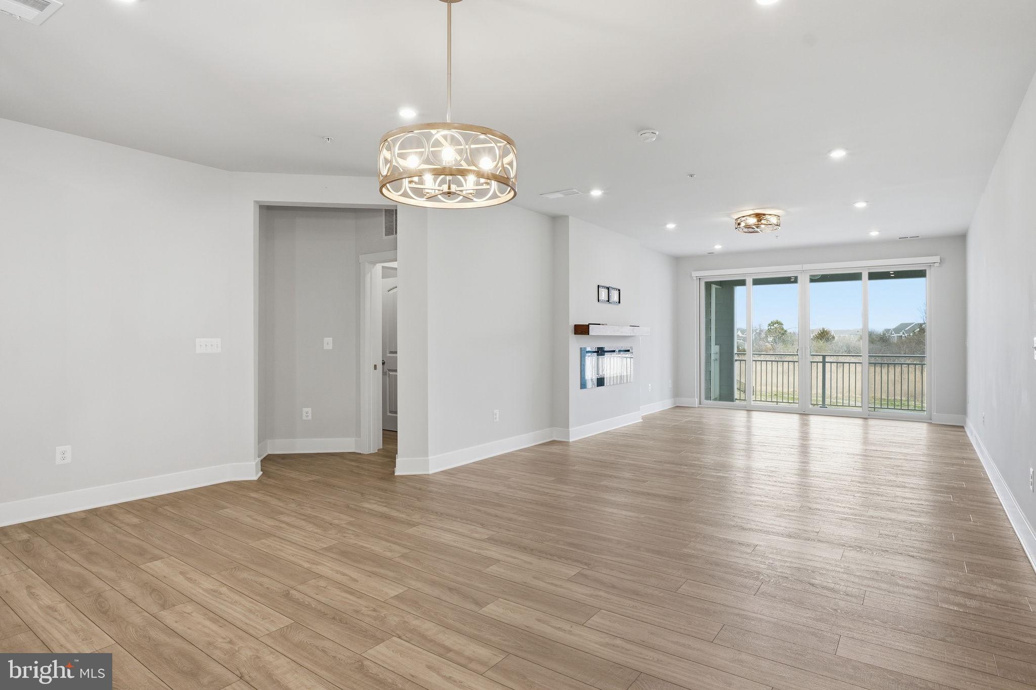 111 Marshgrass Way, Unit 22 Chester, MD 21619 - Photo 13 of 102 a view of an empty room with wooden floor and a window