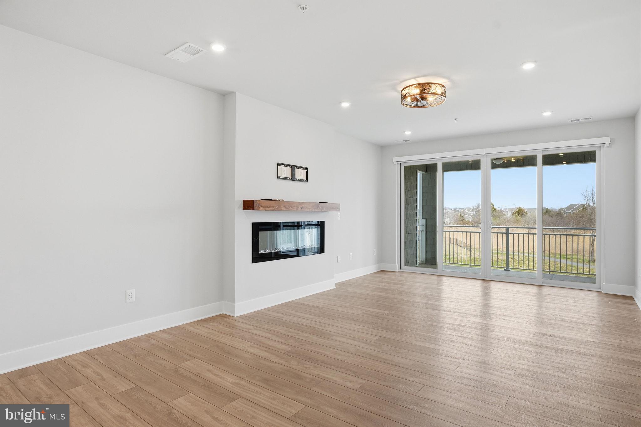 111 Marshgrass Way, Unit 22 Chester, MD 21619 - Photo 14 of 102 a view of an empty room with wooden floor and a window