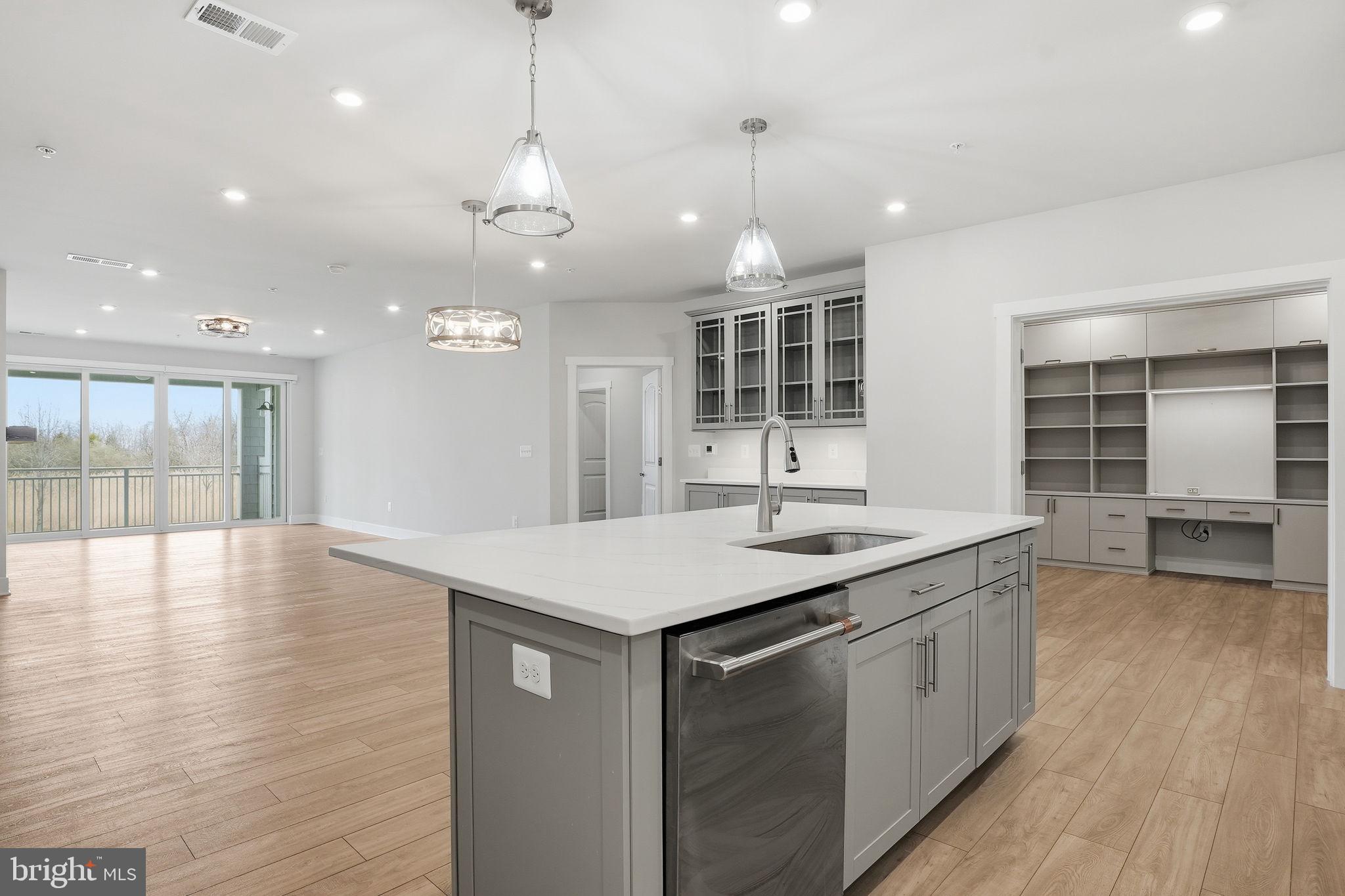111 Marshgrass Way, Unit 22 Chester, MD 21619 - Photo 9 of 102 a kitchen with stainless steel appliances granite countertop a sink a oven a dining table and chairs with wooden floor