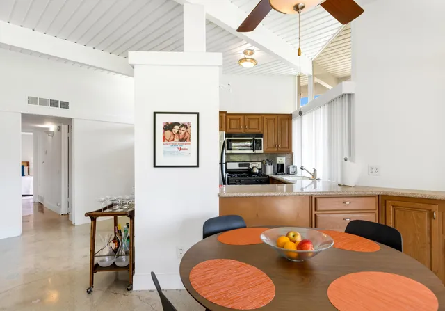 a kitchen with stainless steel appliances granite countertop a dining table chairs and a refrigerator