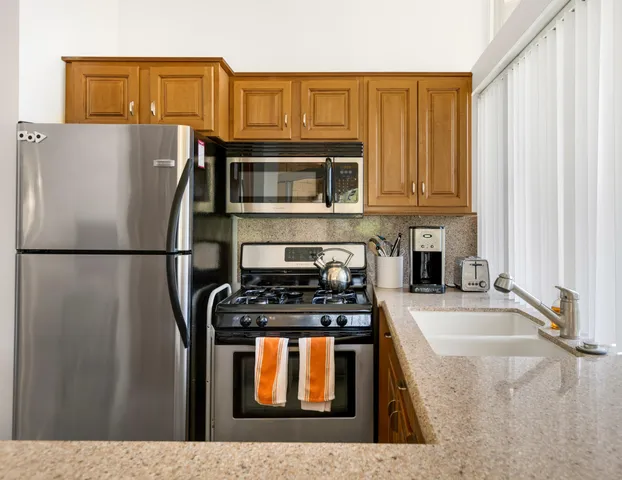 a kitchen with stainless steel appliances granite countertop a refrigerator a stove a sink and a microwave