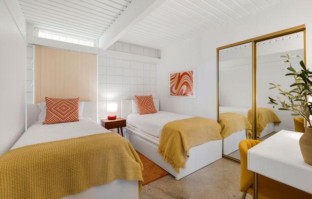 a bedroom with two beds and painting on the wall