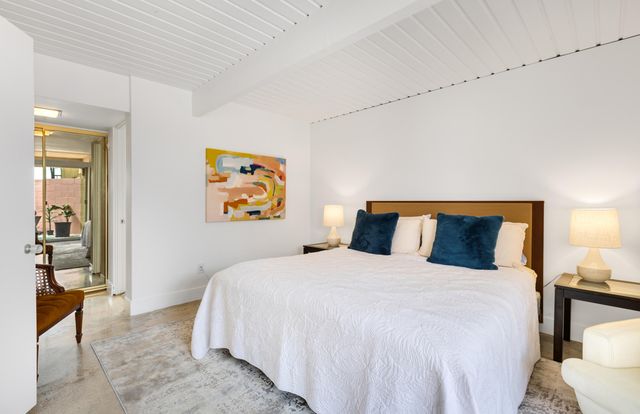 a bedroom with a large bed and a lamp on dresser