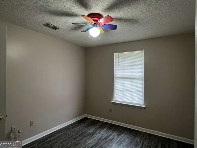 an empty room with wooden floor and a chandelier fan