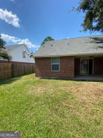 a view of a yard with a large tree and wooden fence