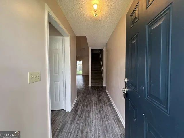 a view of a hallway with wooden floor and a bathroom