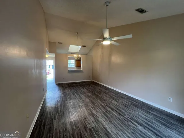 an empty room with wooden floor fan and window