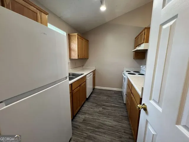 a kitchen with wooden floor and electronic appliances