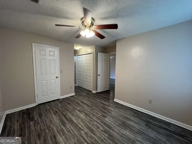 an empty room with wooden floor fan and windows