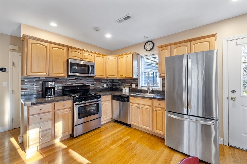 11 Spring Road, Unit B Arlington, MA 02476 - Photo 6 of 19 a kitchen with granite countertop stainless steel appliances a refrigerator cabinets and a window