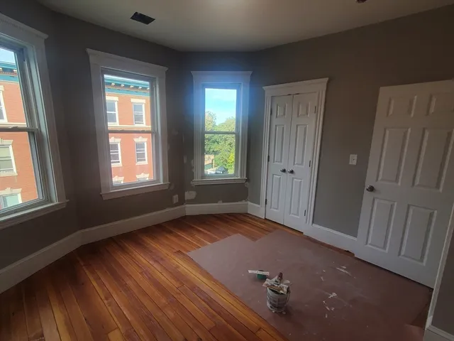 an empty room with wooden floor and windows