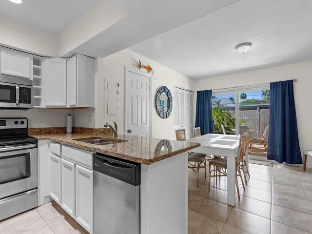 a kitchen with stainless steel appliances granite countertop a stove top oven a sink a dining table and chairs