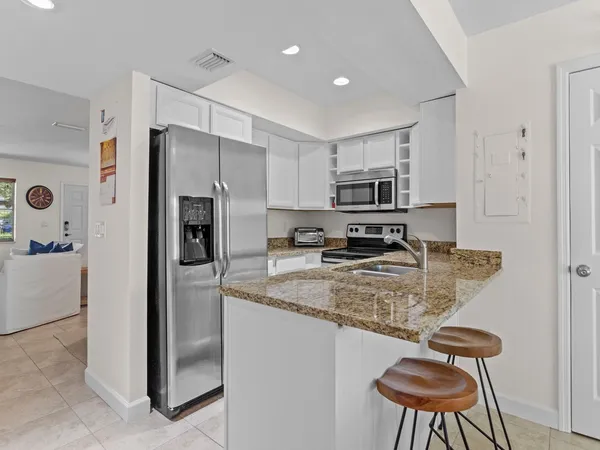 a kitchen with a refrigerator a microwave a stove and chairs