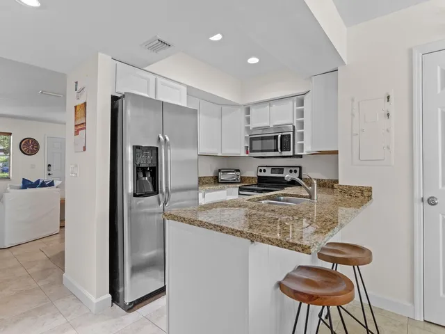a kitchen with a refrigerator a microwave a stove and chairs
