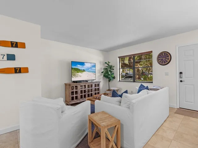 a living room with furniture a clock on wall and a window