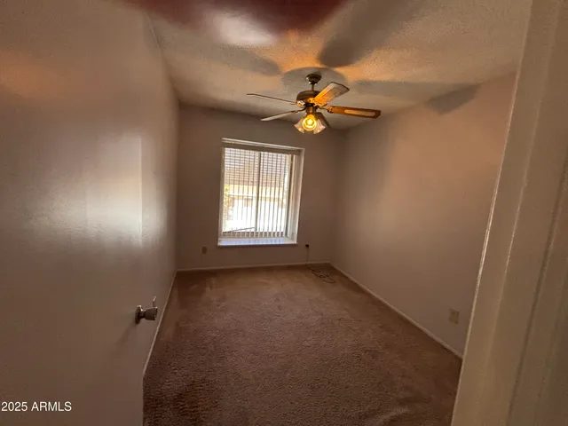 an empty room with windows and fan