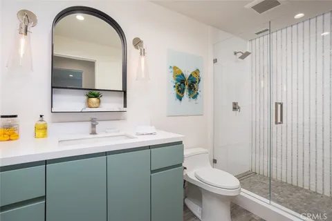 a bathroom with a granite countertop sink a toilet a mirror and shower