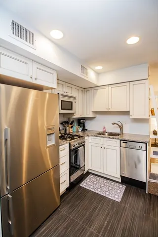 a kitchen with granite countertop a refrigerator stove top oven and sink