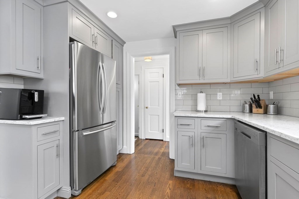 10 Standish Road Milton, MA 02186 - Photo 11 of 28 a kitchen with white cabinets stainless steel appliances and wooden floors