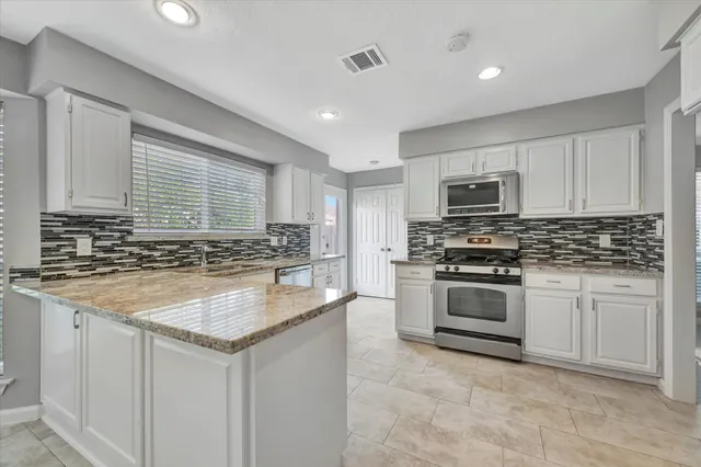 a kitchen with stainless steel appliances granite countertop a sink stove and microwave