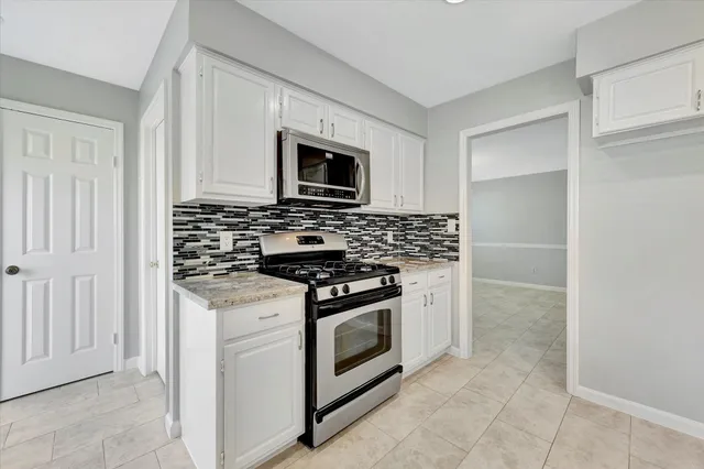 a kitchen with stainless steel appliances granite countertop white cabinets a microwave oven and a refrigerator