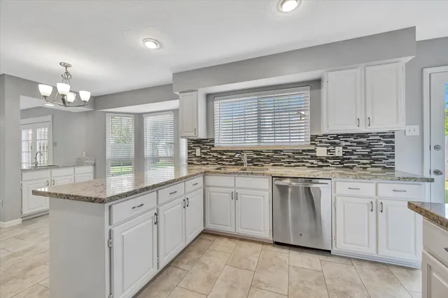 a kitchen with granite countertop white cabinets white appliances a sink and a window
