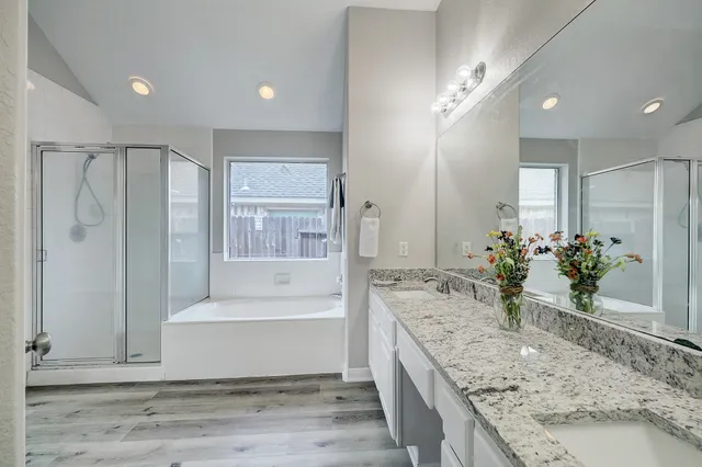 a spacious bathroom with a granite countertop tub a mirror and shower