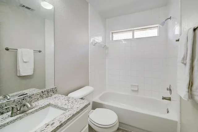 a bathroom with a granite countertop sink a toilet and shower