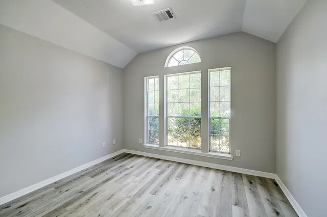an empty room with wooden floor and windows